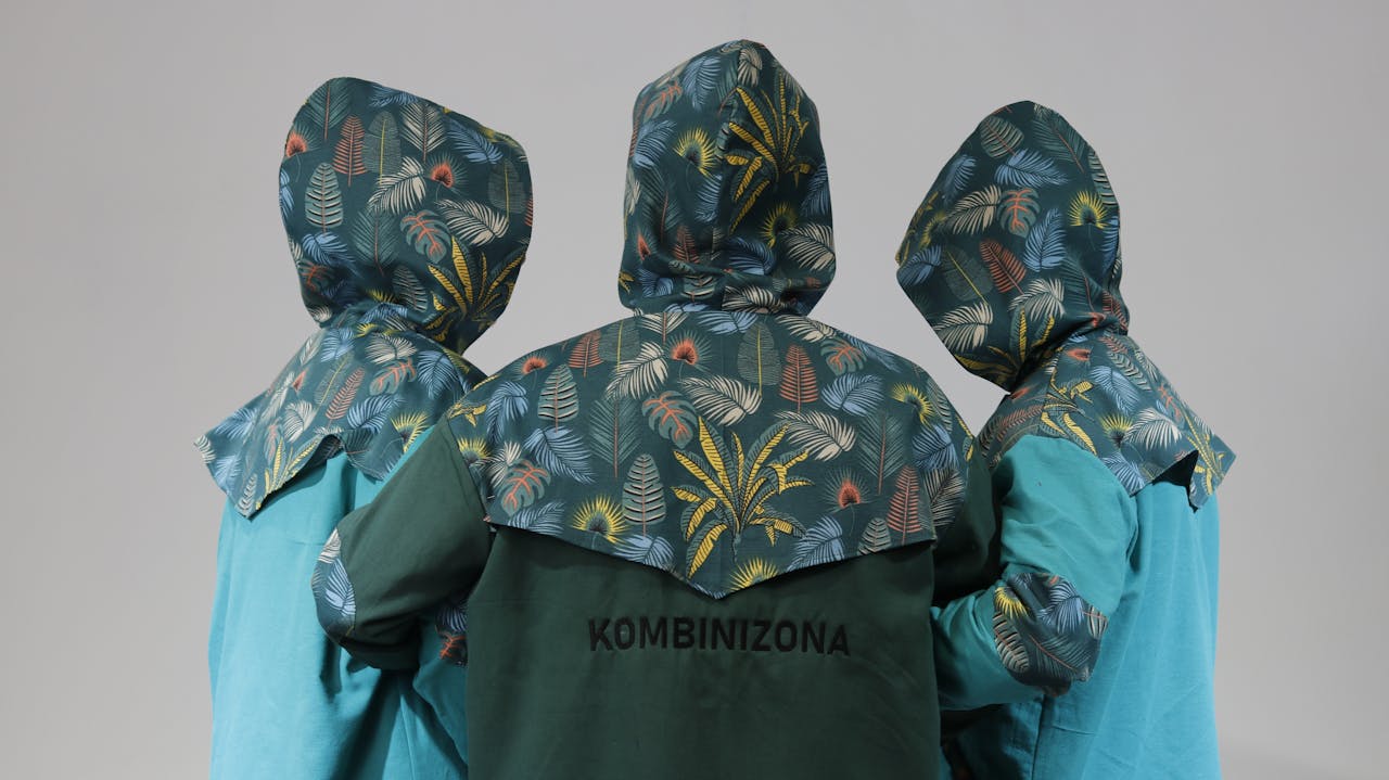 about-01 Three people in stylish floral patterned raincoats viewed from behind in a studio setting.